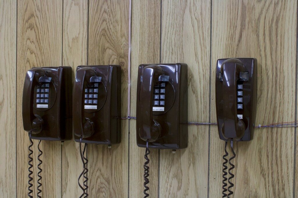 Four brown wall telephones on wooden panels